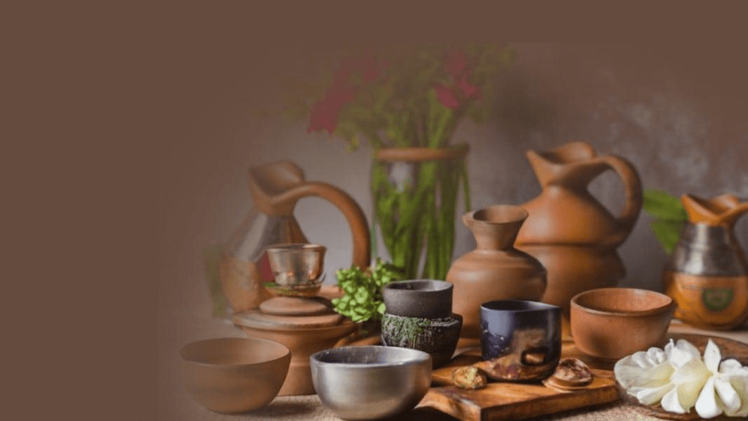 A collection of handmade ceramic and clay pots and cups rests on a wooden surface -  display of Indi